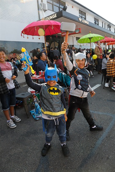 Two young boys smiling and posing while wearing Batman and Thor costumes