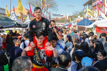 Lion dancers shoulder riding one another amongst crowd of guests