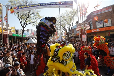 Crowd of guests watching lion dancers in colourful costumes performing