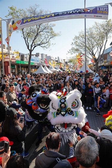 Crowd guests watching and petting white and black lion dancing puppets performing