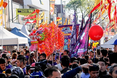 Dragon dancers performing with bright red puppet amongst crowd of guests