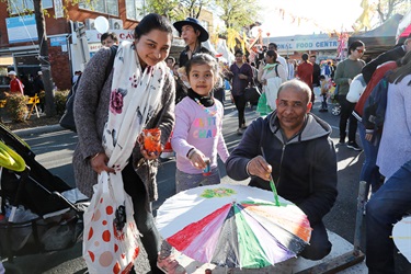 Family smiling and posing while decorating paper umbrella with paint and glitter