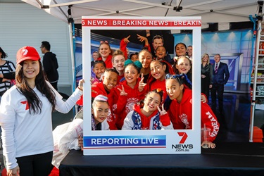 Young girls in Kookies N Kream dance team smiling and posing with 7 NEWS photo frame prop