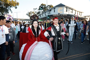 Crowd of guests watching young woman and man wearing Moon Goddess and Sun Shooter costumes