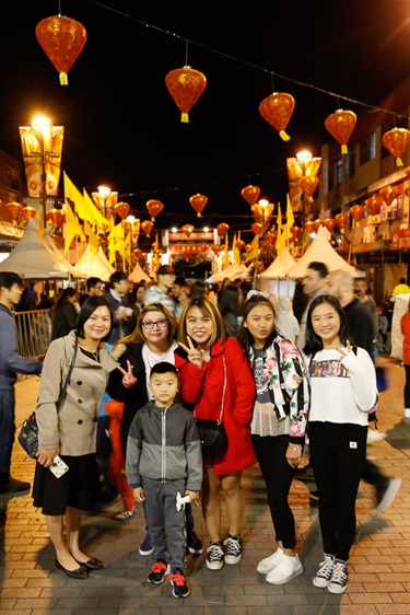 Family smiling and posing under red and yellow lanterns, at Freedom Plaza