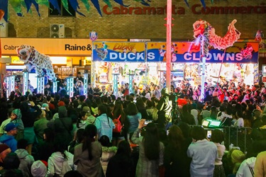 Crowd of guests watching lion dancers wearing white costumes performing on stilts