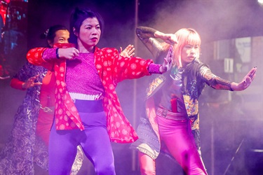 Group of women wearing contemporary adaptations of traditional cultural clothing performing dance on the stage