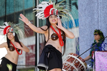 Young women wearing traditional Polynesian costumes performing dance on the stage