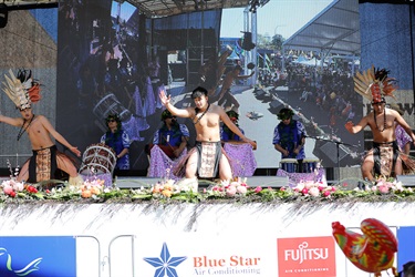 Young men wearing traditional Polynesian costume performing dance on the stage
