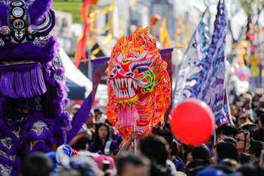 Bright red dragon dancing puppet amongst the crowd of guests