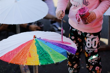 Young girl painting different colours onto paper umbrella