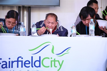 Group of people sitting at a table and eating Vietnamese noodle dish