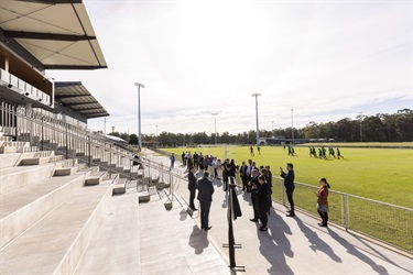 Mayor Frank Carbone making a speech at the Fairfield Showground Pavilion with a soccer team training in the background