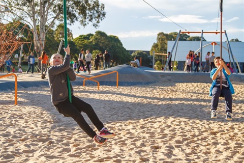 kids playing at Adventure Park swinging over sand