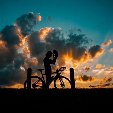 silhouette of man riding a bike in the sunset