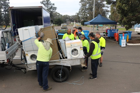Spring clean workers unloading a trailer with household items such as a dryer