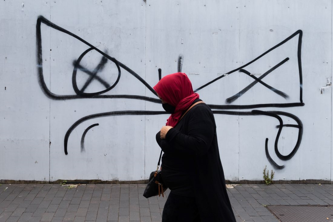 Woman walking past a grafitti wall.