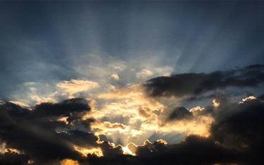 photo of sunbeams coming through the clouds during a sunset
