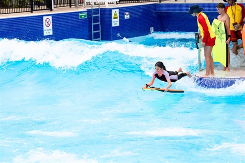 young girl on boogie board enjoying the new wave pool at Aquatopia