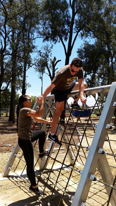 Two people climbing over netting obstacle in obstacle course