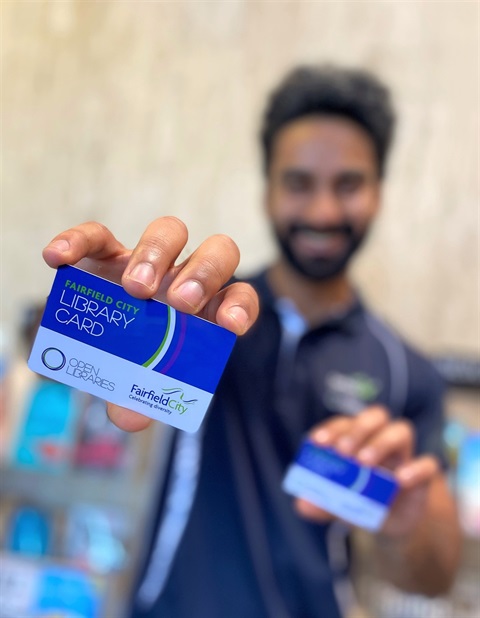 Open Libraries staff member smiling while holding a Fairfield City library card in each hand