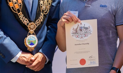 A Mayor standing next to person holding up an Australian Citizenship certificate