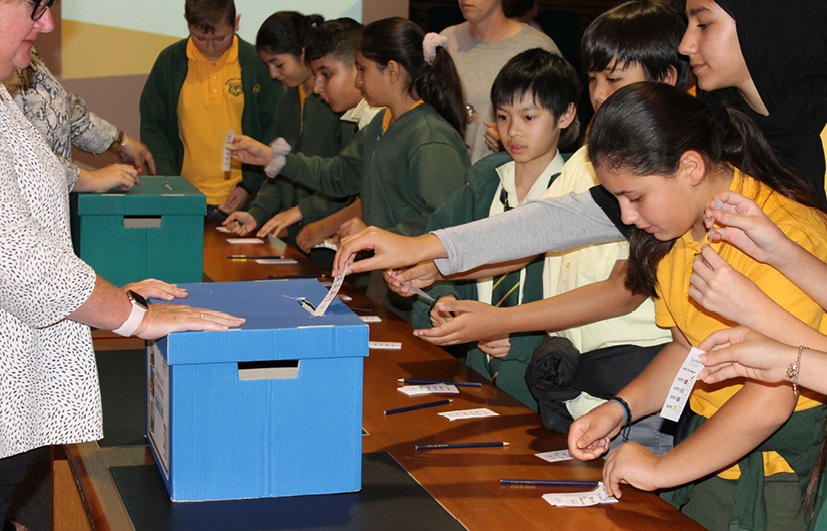 School children submitting paper votes into ballot box