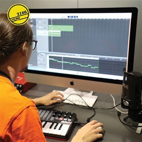 A person creates music production on the iMac computer
