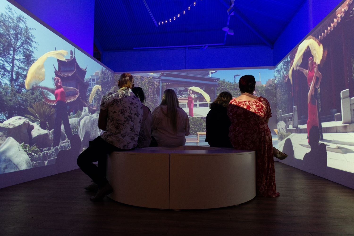 Five people watching a video exhibition of Niramsin Yakou, Fairiety Show, 2022. Image credit Helene C.