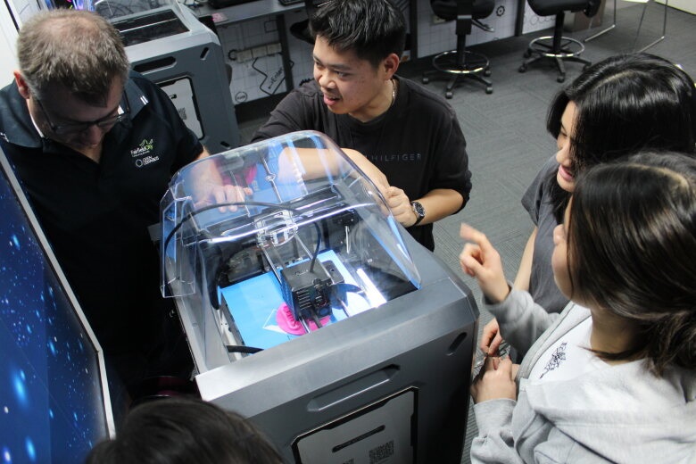 Digital printer surrounded by people watching it printing