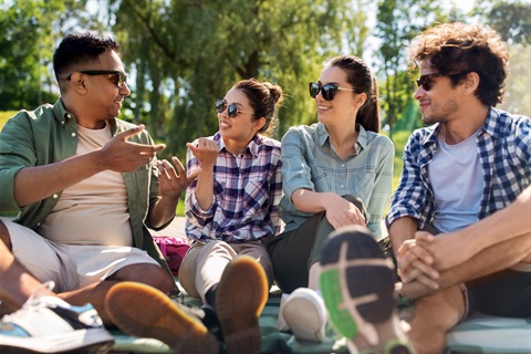 Group of four young adults sitting in the sun and having a conversation
