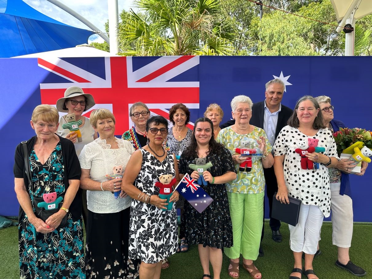 knitting group taking a photo with the mayor showing their awards