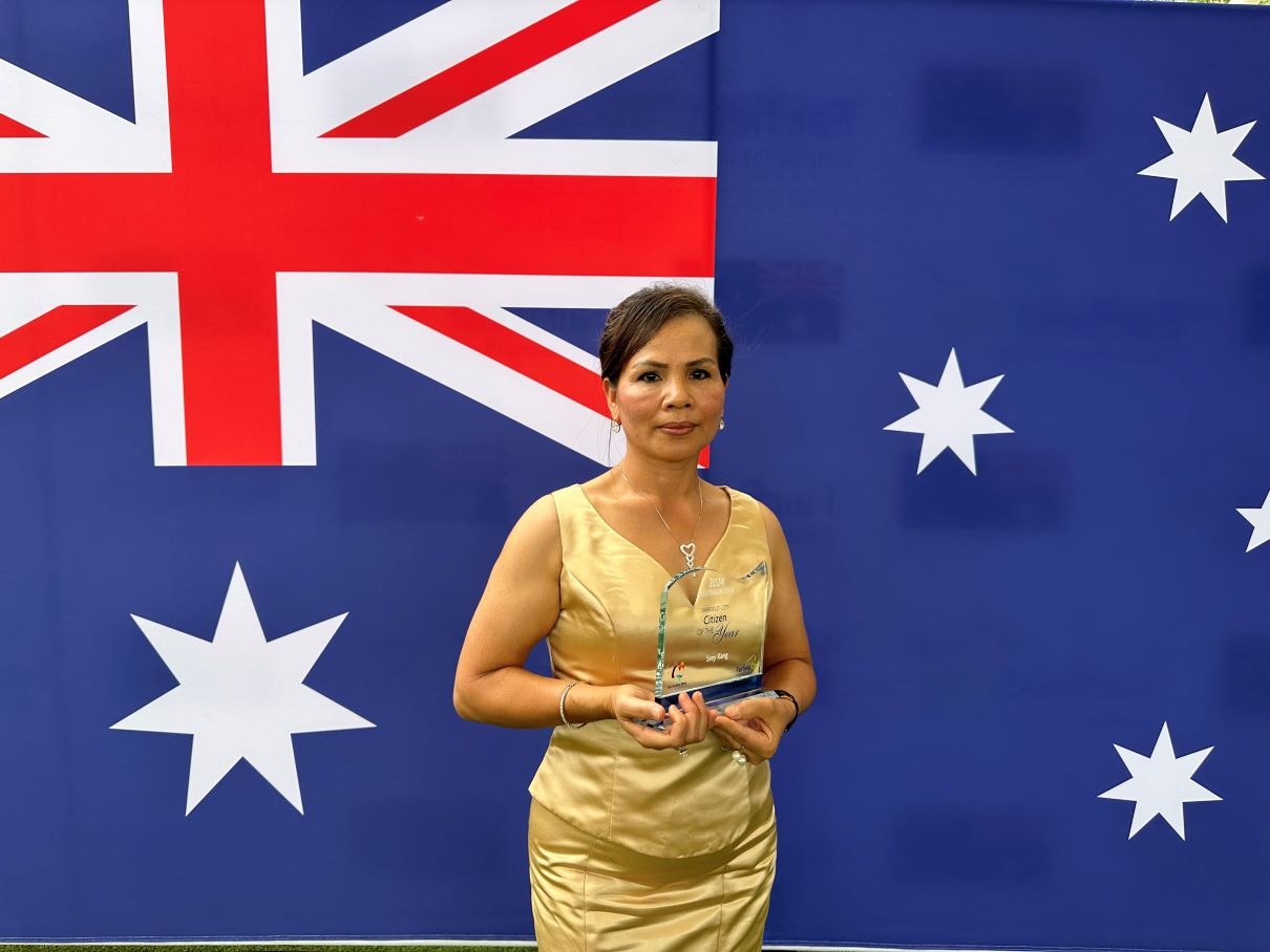 Portrait of Srey Kang holding up the Citizen of the Year award