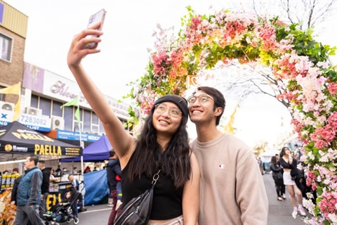 A couple taking a photo under the floral arch