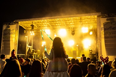 Illuminate stage with girl holding up lightsabres.