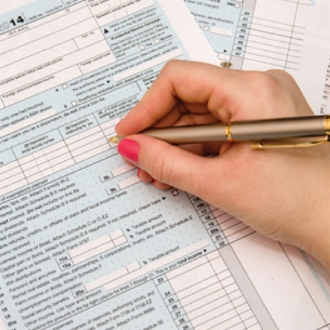 Close up of someone holding a pen filling out a form