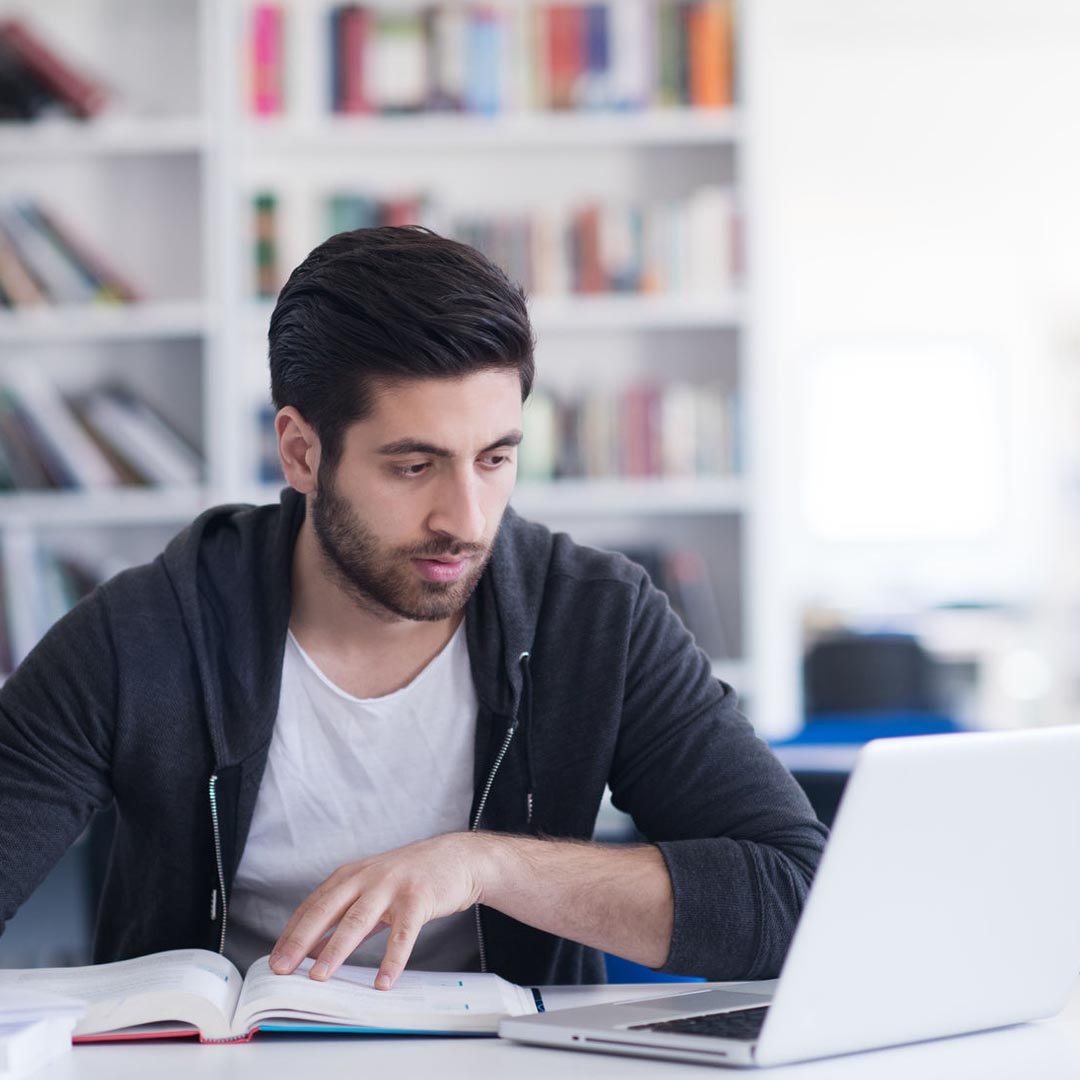 Young man studying and writing notes while using his laptop