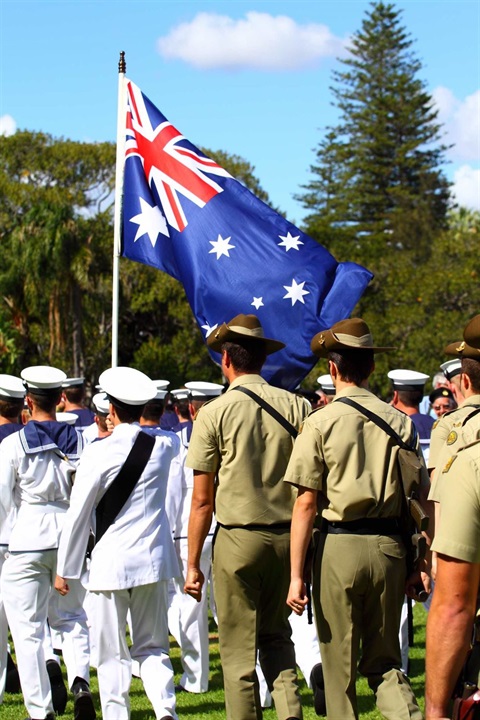 Men in military uniform stand together during an ANZAC Day commemoration, reflecting on their service and remembrance.