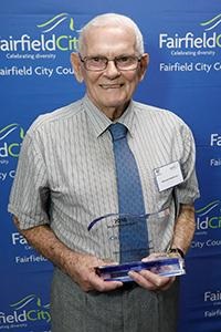 Desmond Ettingshausen holding up Citizen of the Year Award
