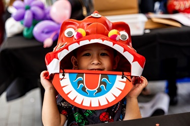A kid underneath a decorative lion head toy