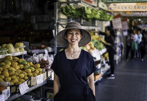 Woman posing in front of fruit and vegetable stand