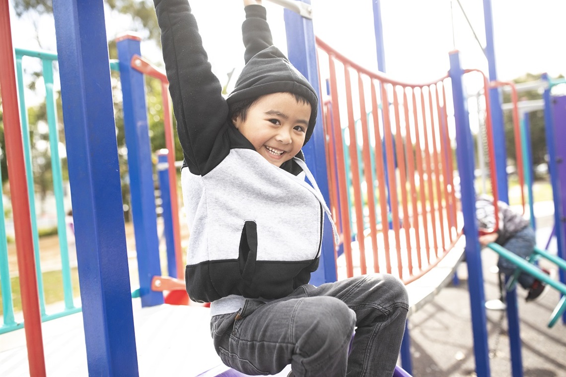 Young boy smiling and playing on playground set