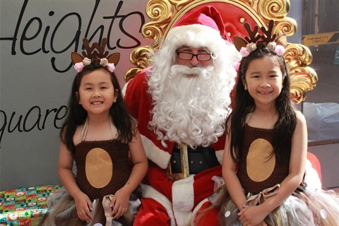 Two young girls smiling with Santa at the Canley Heights Children's Christmas Party
