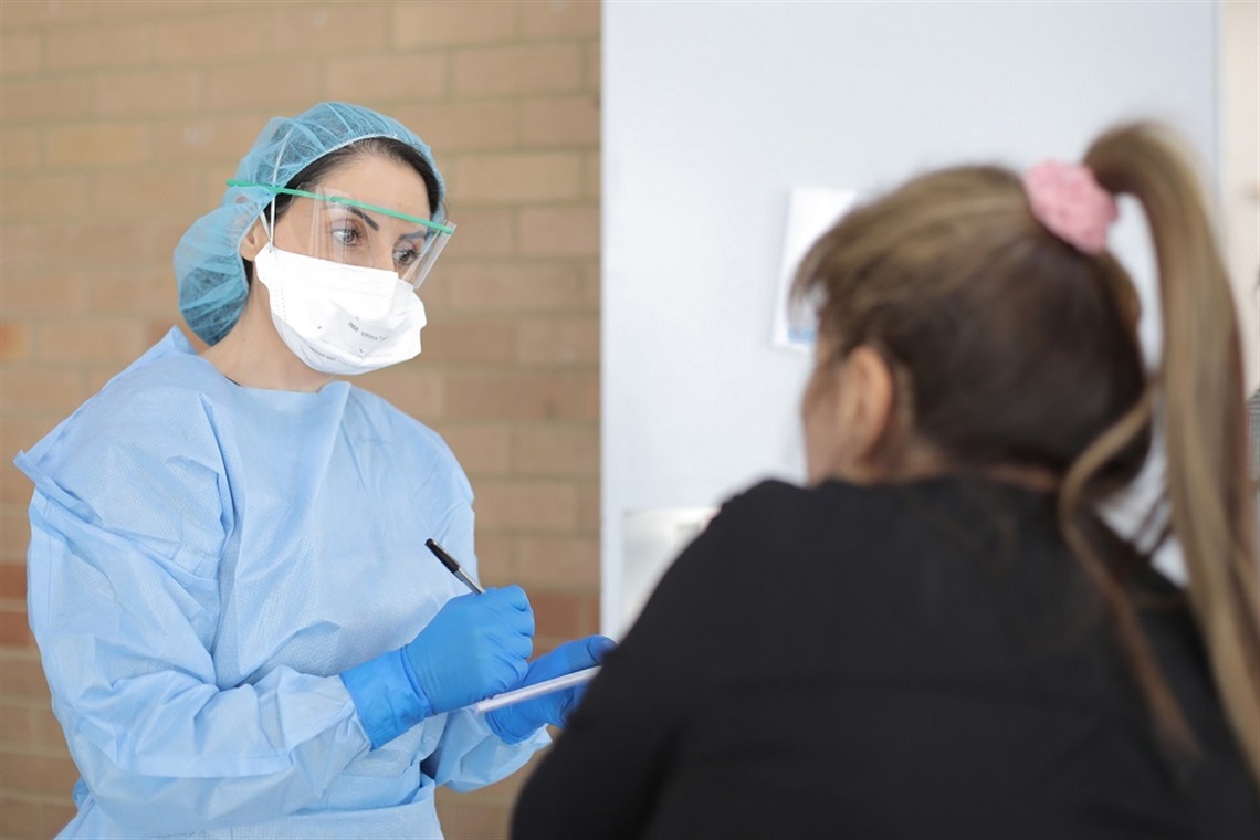 lady in mask with clipboard with another lady 