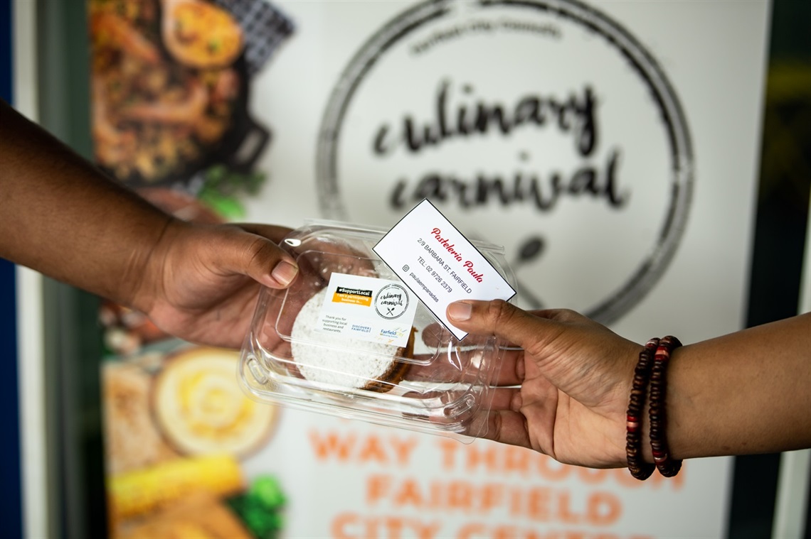Hands holding up boxed food in front of Culinary Carnival Festival logo