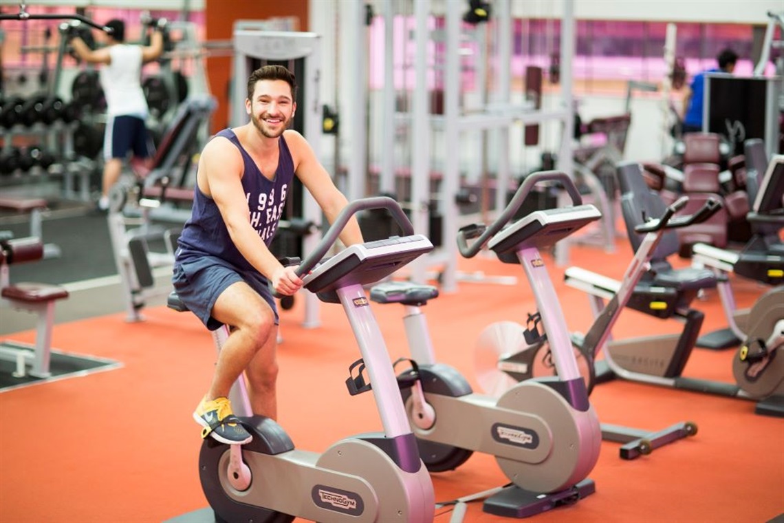 Young man smiling while using exercise bicycle in the gym at Fairfield Leisure Centre