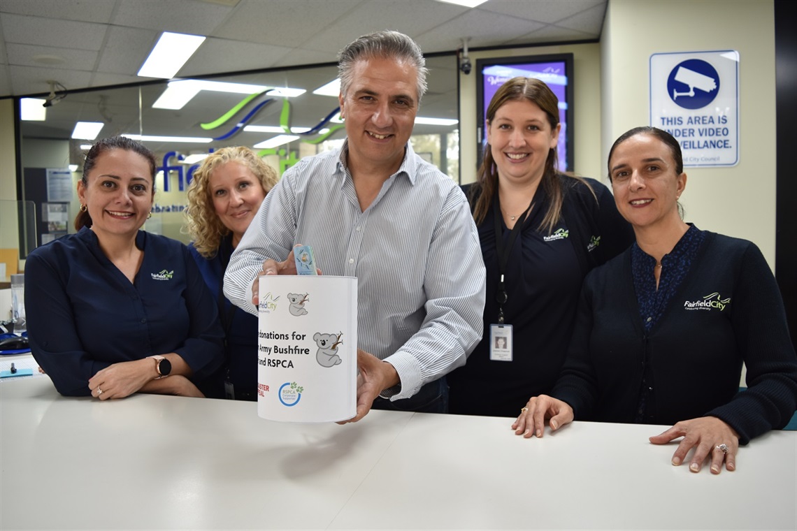 Mayor Frank Carbone smiling and posing with Fairfield City Council staff while holding one of the bushfire relief collection tins