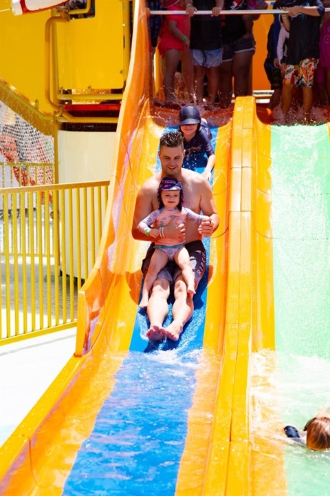 Father and daughter going down water slide together