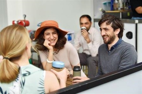 Group of people talking to one another while holding reusable keep cups