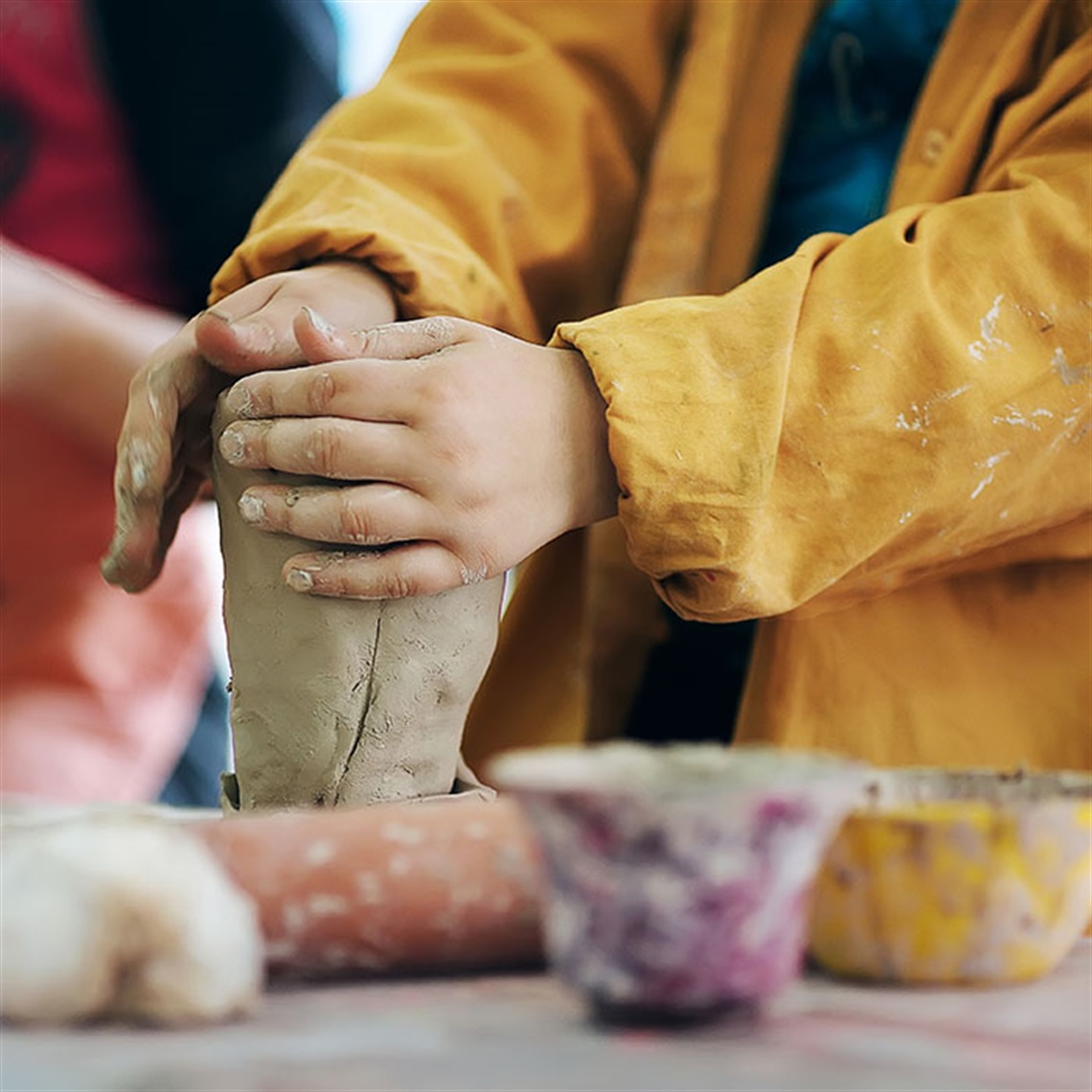 Young child using their hands to shape and smooth a block of clay